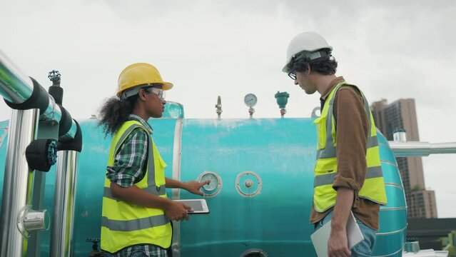 Two Professional engineer man and women working checking and maintenance pipeline construction top of the building. Worker in safety uniform using tablet at pipeline construction system