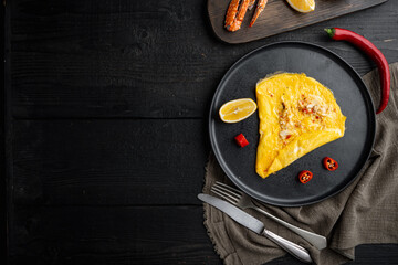 Fried breakfast omelette with crab meat and cheese, on plate, on black wooden table background, top view flat lay  , with copyspace  and space for text - obrazy, fototapety, plakaty