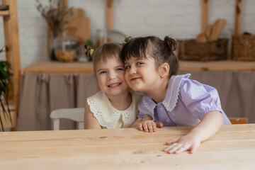 portrait of two cute little girls in beautiful dresses sitting in the kitchen. card, space for text