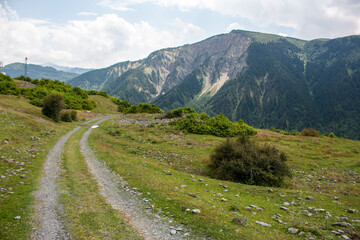 Double gray trail with view of the mountains entering the town of Tsaldashi, during the trek from the town of Mestia to Ushguli, in Geogia.