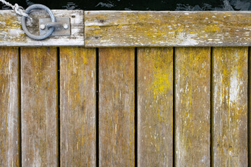 Old weathered wooden pier with a metal mooring ring. Copy space. Top view. 