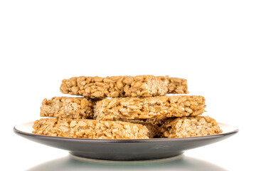 Several sweet roasted sweets from sunflower seeds and honey on a ceramic saucer, macro, isolated on a white background.