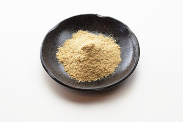 Nuka powder.  Mound or heap of Nuka on a black plate, used in making nukadoko, which is a rice bran for making Japanese fermentation or pickling of vegetables. Isolated on pure white.