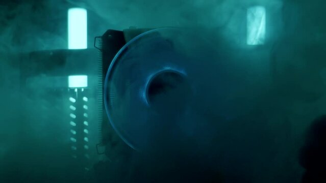 Close-up moving macro shot of the blue spinning glowing cooler, around which thick steam flows. Movement from the general plan of motherboard on gaming computer to center of cooler fixed on heatsink