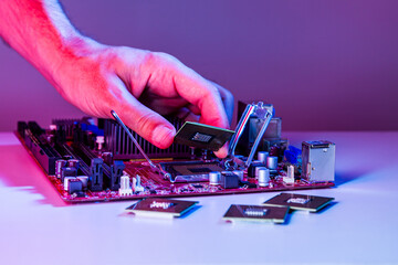 A man's hand inserts a processor into the motherboard chipset