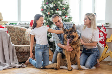 happy family and cute dog having fun at christmas tree. atmospheric emotional moments. merry christmas and happy new year concept.