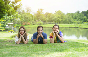 Fototapeta premium group of friends having a picnic in the park on vacation, joyful young friends lying on lawn together and looking at camera