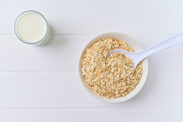 bowl of granola with a spoon and a glass of oat milk. white wooden background. top view. copy space.
