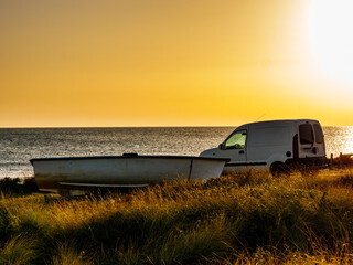 Fishing boat and car on sea shore