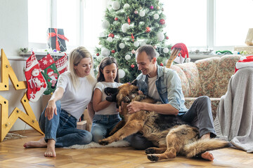 happy family and cute dog having fun at christmas tree. atmospheric emotional moments. merry christmas and happy new year concept.