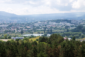 Panoramic top view of the city of Kislovodsk in Russia with green trees and architecture through a misty haze on a sunny summer day and a sky with clouds