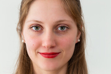 Naklejka premium Portrait of smiling young woman looking to the camera in office with white background. Female human looking into the camera in horizontal composition.