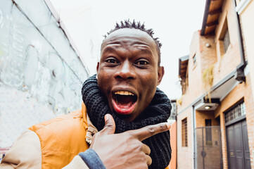 closeup portrait of young african man in the street with a big smile looking at the camera.