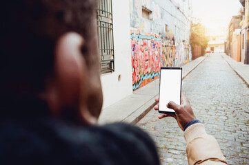 rear view of man in the street looking at the screen of his phone