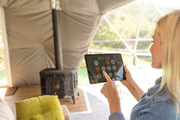 woman holding a tablet computer with system clever house on a screen on the background of the house