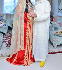 Moroccan wedding. A groom wearing a djellaba holds his bride who is wearing a traditional Moroccan caftan