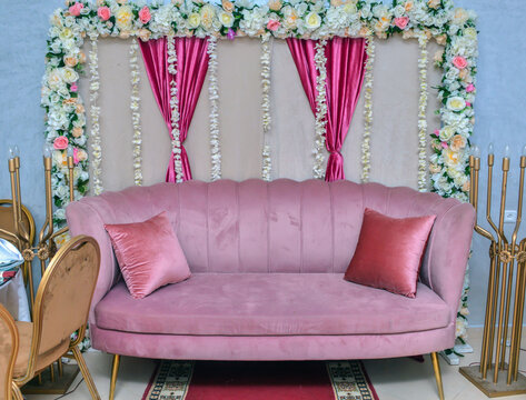 Wedding dinner table decor. Indian reception or banquet. Pastel and white colors. Beiege sofa for Hindu newlyweds. Burning candles as a centerpiece.