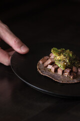 hand holding a dish with a cow tongue taco