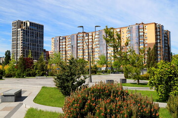 Beautiful park against tall houses, buildings. skyscrapers landscape. Spring, summer street in Ukrainian city Dnipro Ukraine