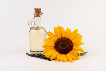 Sunflower oil in glass jug, seeds and flower isolated on white background