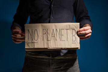 Fototapeta na wymiar man holding a sign at waist height looking at the camera or straight ahead, on which it is written. not planet B 
