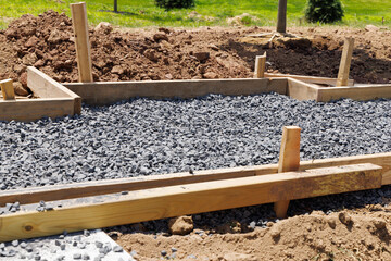A sidewalk is under construction, a concrete curb is being installed and the foundation of the road...