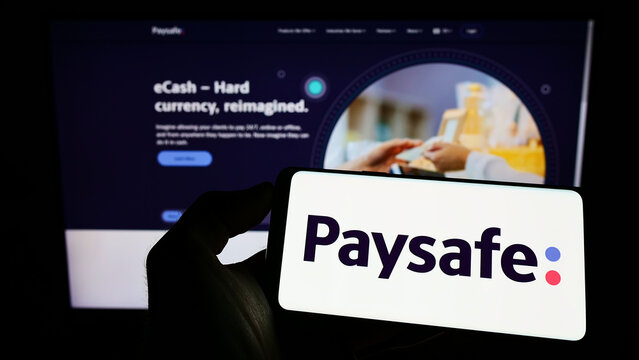 Stuttgart, Germany - 07-31-2022: Person holding smartphone with logo of British payments company Paysafe Group on screen in front of website. Focus on phone display.