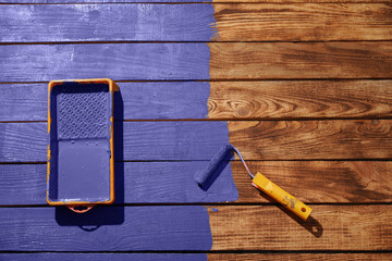 Recoloring, change, renovation concept. Paint tray and a roller with new Veri Pery recoloring wooden planks