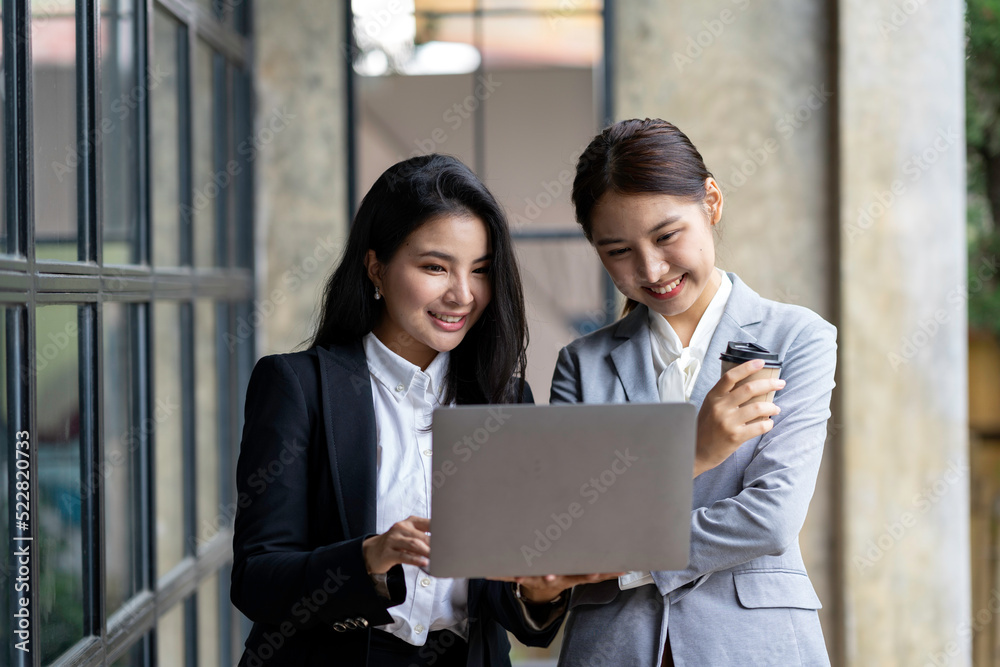 Wall mural two pretty young asian businesswomen standing to discuss working on investment projects and planning