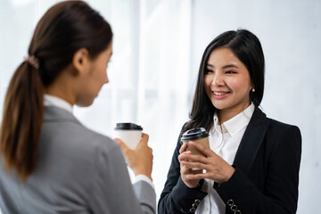 Obraz premium Two Asian businesswoman colleagues drink coffee. and discuss new marketing business strategy projects Meeting to meet professional investors at work. and business finance and accounting concepts.