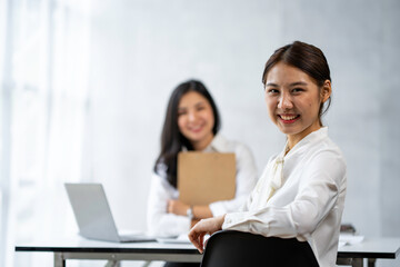 Two young Asian businesswomen talk, consult, discuss working with new startup project idea presentation analyze plan marketing and investment in the office.
