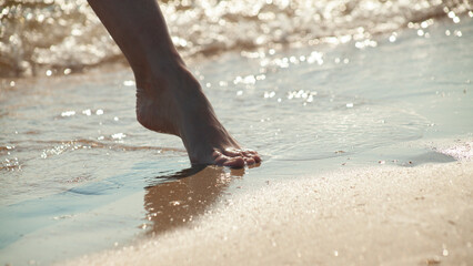 close-up photo of women's feet on the sand near the sea