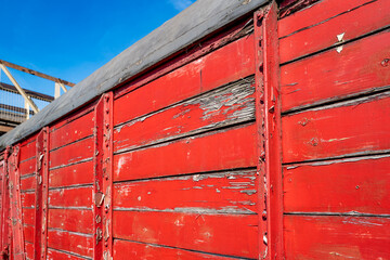 Old and weathered timber built mail railway wagons showing the peeling paintwork. The wagons are seen at a bygone era railway station with a foot bridge just visible.