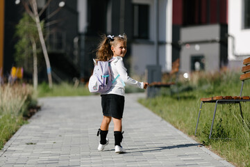 a little girl goes to school through the park along the path. distance education concept. schoolgirl returning home from school
