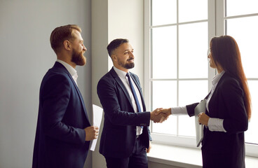 Happy business people meeting and exchanging handshakes. Young man and woman shaking hands, greeting each other, making a deal, or expressing gratitude for professional collaboration and partnership