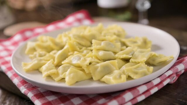 Plin del Piemonte. Small ravioli del plin typical Piedmontese filled pasta from the Langhe in Italy seasoned. Hot steam coming from the plate. High quality FullHD footage