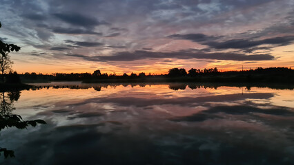 Fototapeta na wymiar beautiful evening sunset on the lake with interesting clouds and orange sky