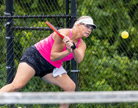 Professional female pickelball player returns a two handed backhand