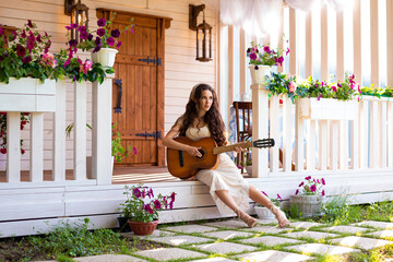 a young woman sits on the doorstep of her house and plays the guitar
