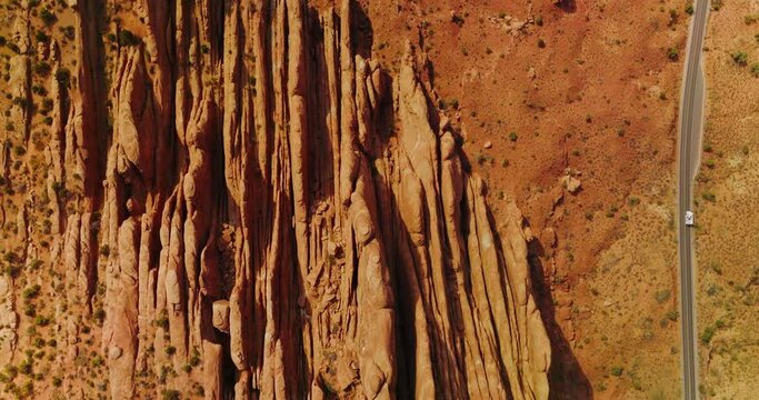 Road going parallel to the beautiful rocks in Arches National Park. Drone flying over the orange landscape in Utah, USA.