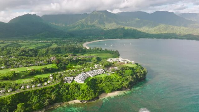 Cinematic Princeville shore with summer beach cottages and oceanfront villas on scenic Hawaii landscape background. Summer vacation in paradise 4K drone. Aerial Hanalei Bay villas on Kauai island 4K