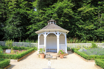 gazebo in the garden with a picket fence.