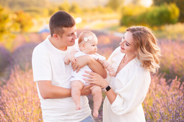 Family portrait mother father and baby on lavender field having fun together. Happy couple with child