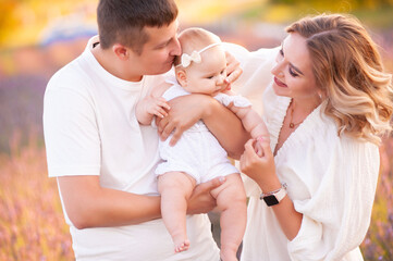 Family portrait mother father and baby on lavender field having fun together. Happy couple with child