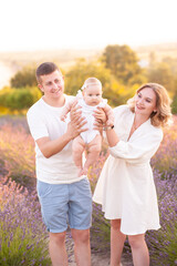 Family portrait mother father and baby on lavender field having fun together. Happy couple with child