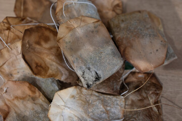 Top view of a bunch of used tea bags. Several used tea bags in a heap. Used tea bags for re-using as a compress, to acidify oil, to revitalize puffy eyes, a facial steam, deodorize a fridge