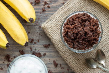 Maulwurfskuchen im Glas mit Stracciatella und Banane auf einem Tisch aus Holz