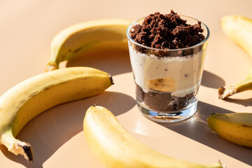 Maulwurfskuchen im Glas mit Stracciatella und Banane auf einem orangen Untergrund