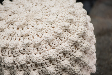white pouf with knitted decorative ornament, fabric close-up.