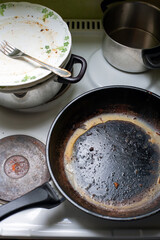 greasy old pan and dirty dishes on a stove